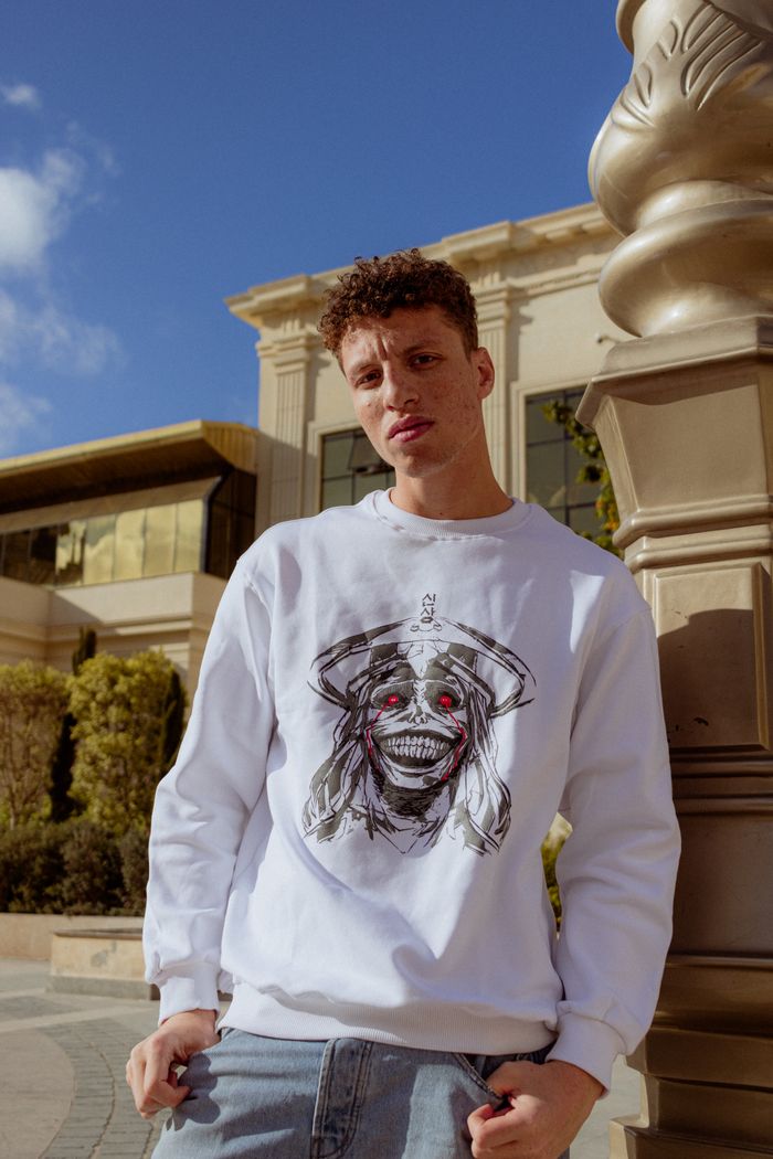 Young man in graphic sweatshirt posing outdoors in sunny Egypt setting.